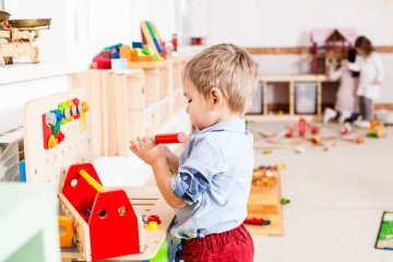 Mały chłopiec bawi się w przedszkolnej sali.