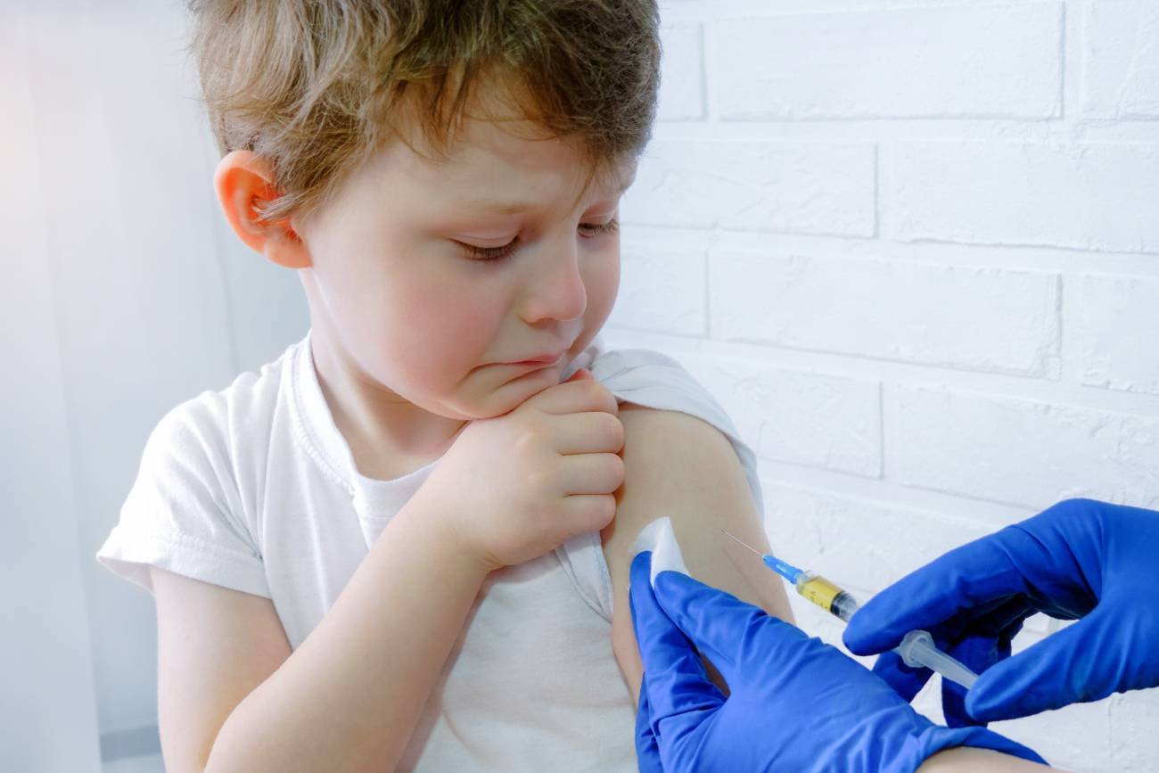 Chłopiec w wieku przedszkolnym podczas szczepienia przeciw krztuścowi.
