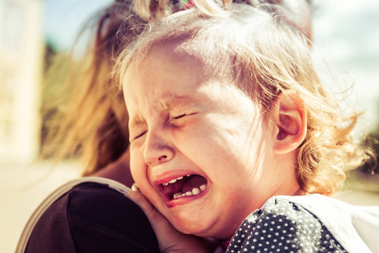 Płaczące małe dziecko w ramionach mamy.