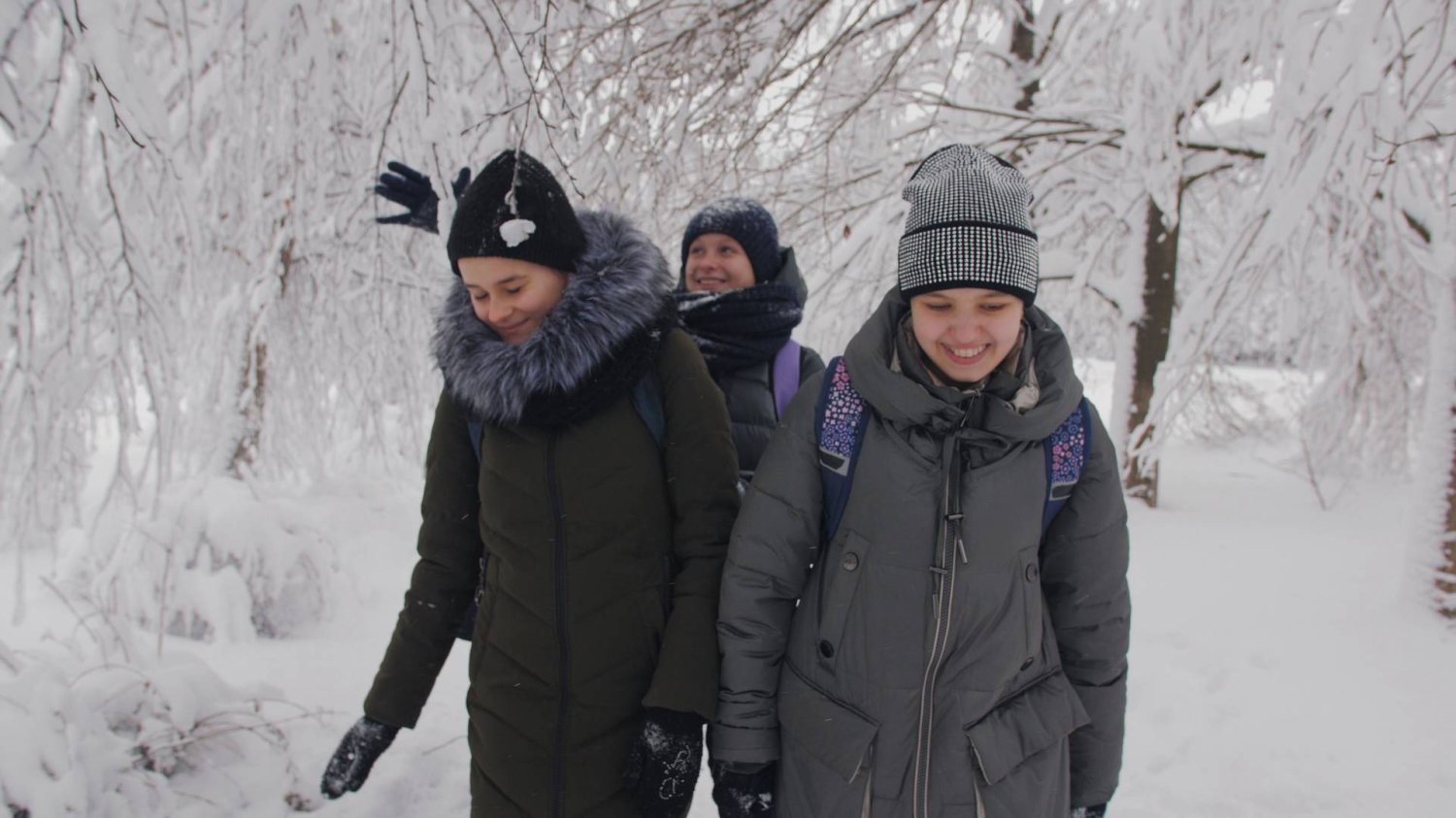 uczniowie idą z plecakami przez śnieg