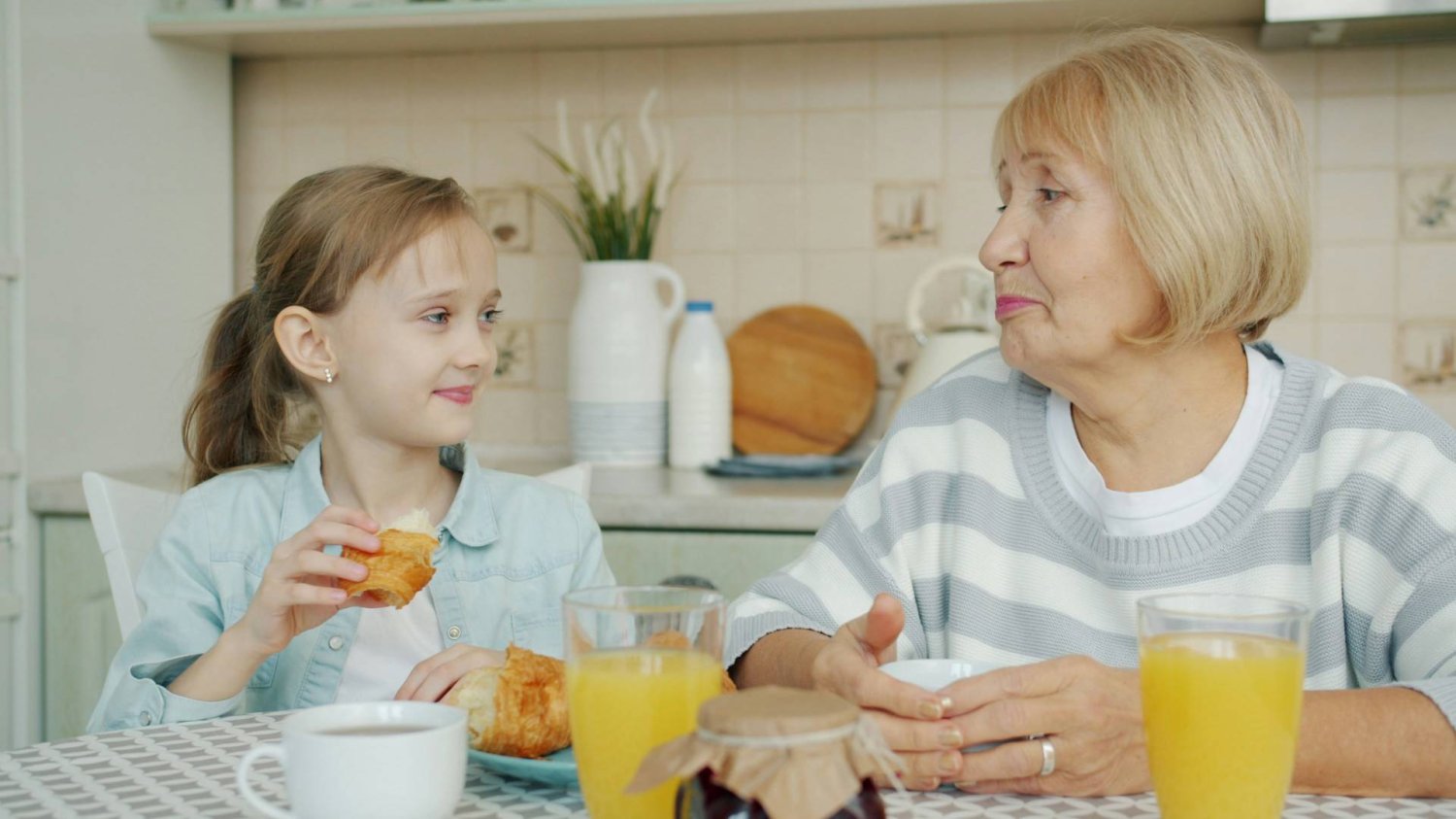 babcia z wnuczką przy kuchennym stole jedzą posiłek