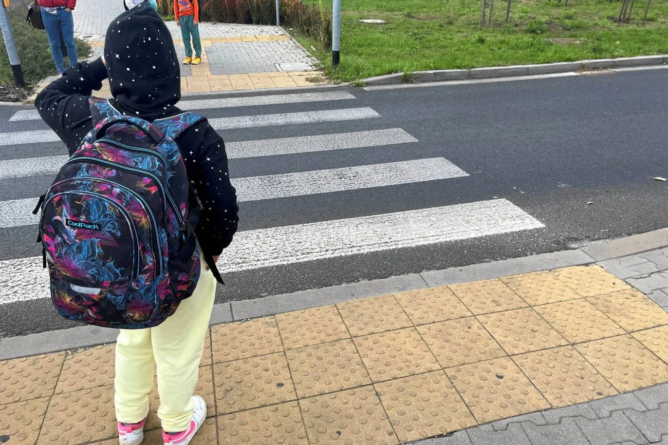 Uczeń przechodzi przez ulicę do szkoły.