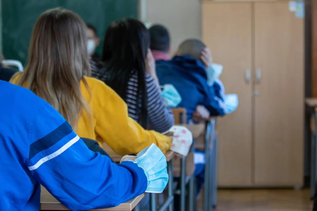 Uczniowie siedzą w ławkach na lekcji.