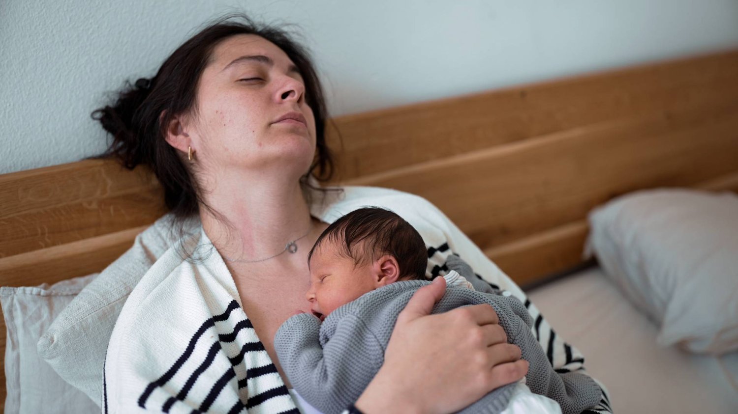 młoda mama śpi z noworodkiem na piersiach