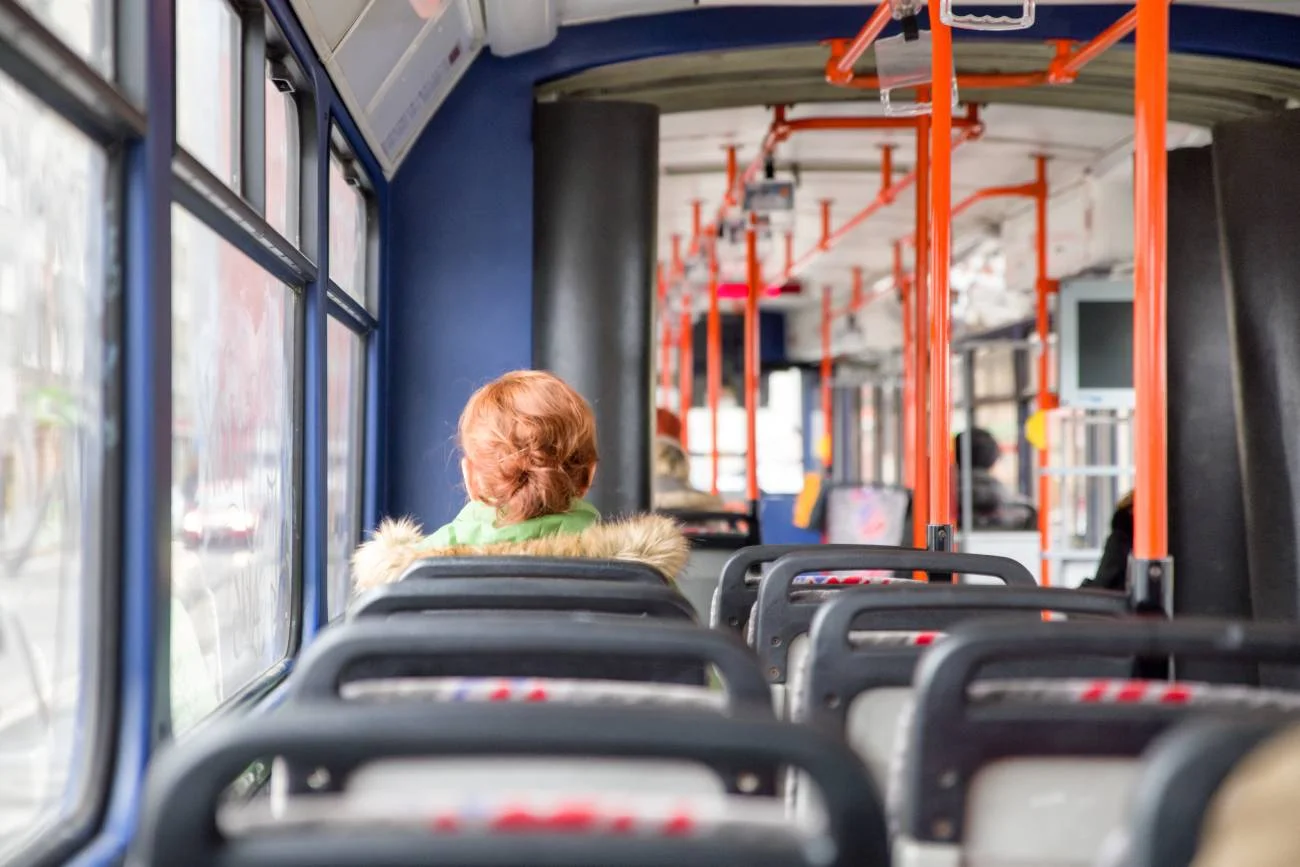 Starsza kobieta jadąca autobusem miejskim.