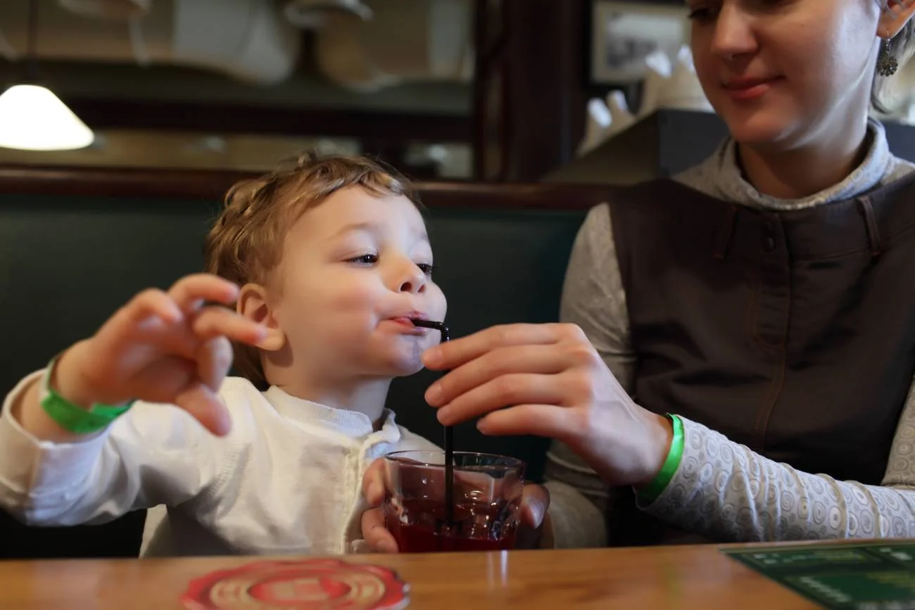 Mały chłopiec w restauracji pije napój.