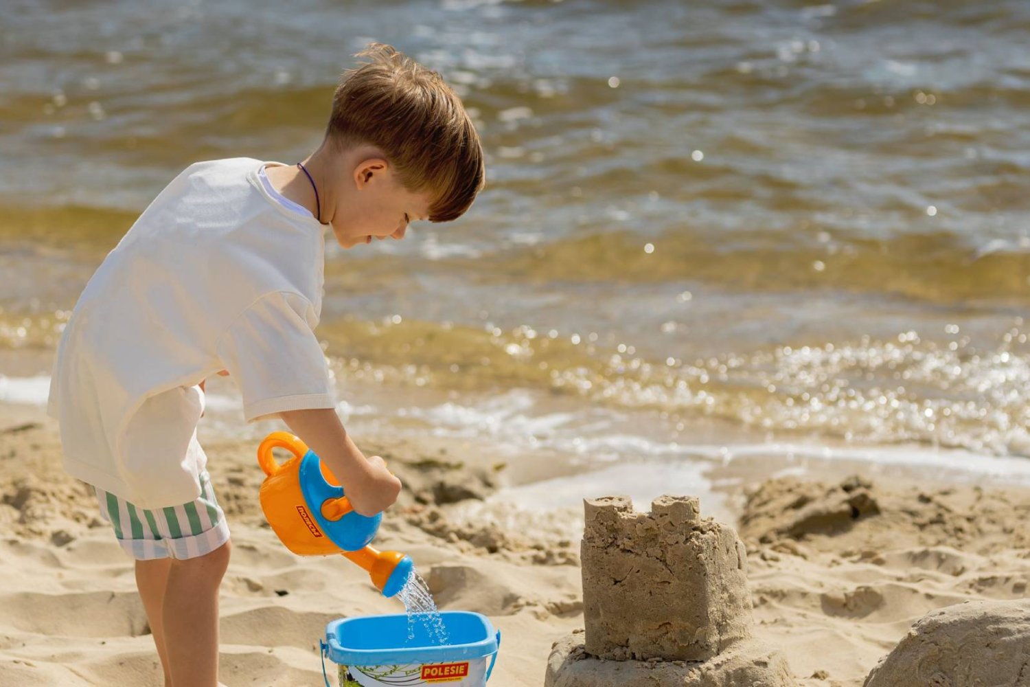 chłopiec na plaży nad morzem bawi się w piasku