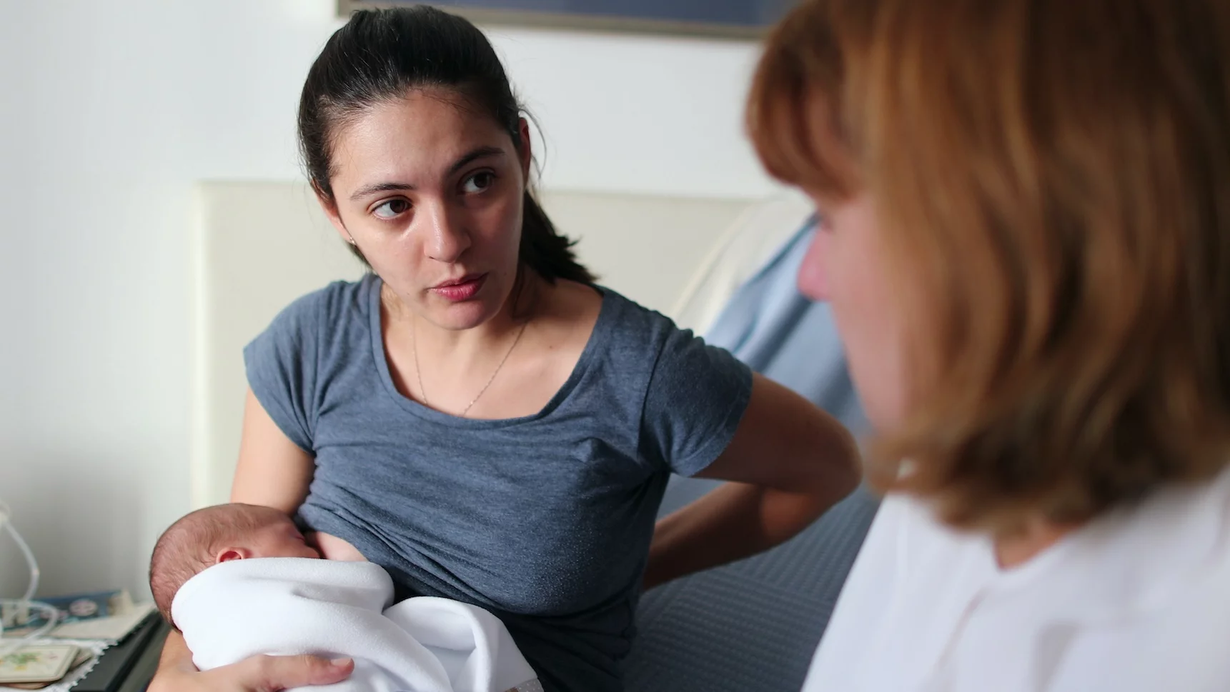 Kobieta karmi piersią i konsultuje się z położną