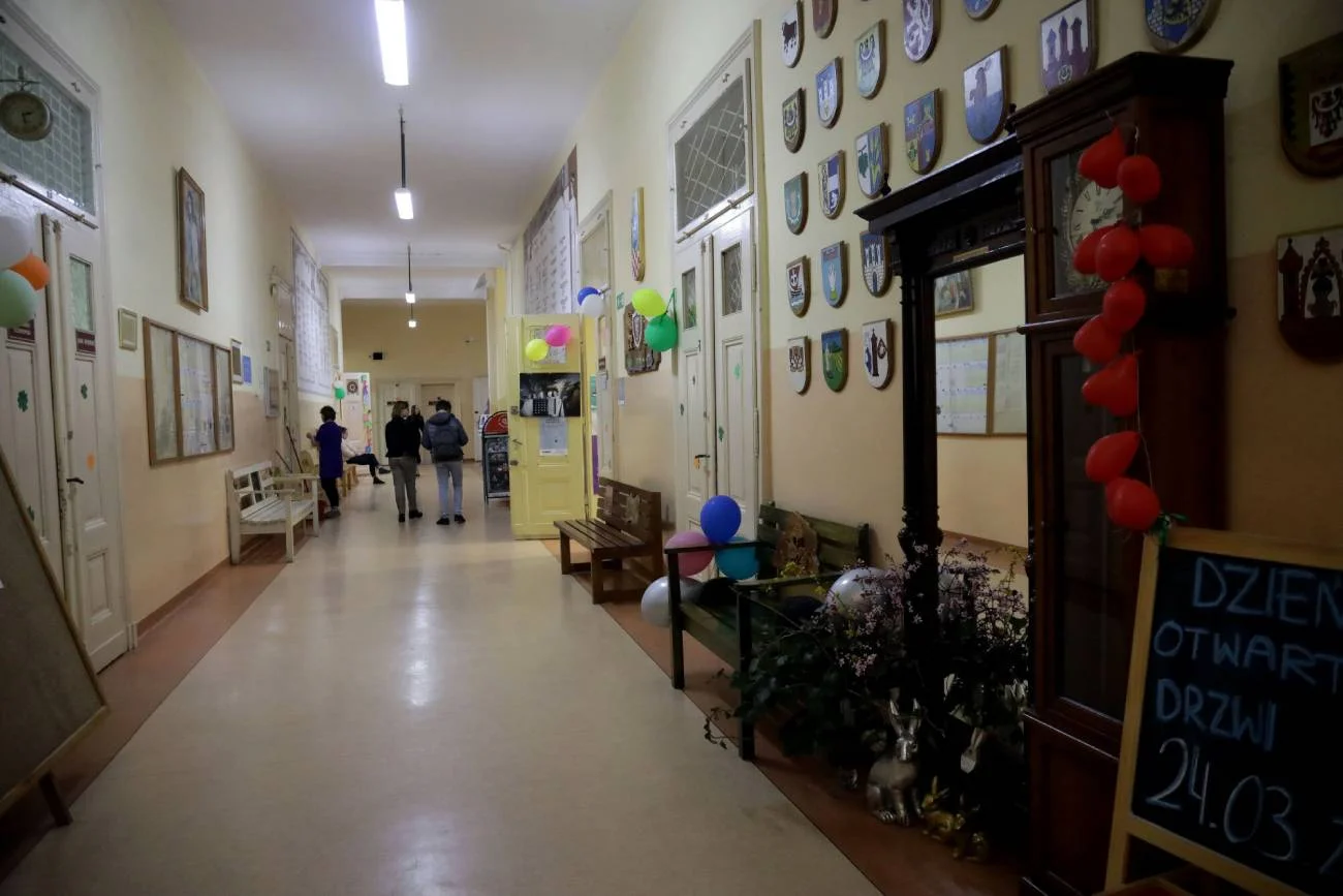 Młodzież na szkolnym korytarzu idzie na lekcje.