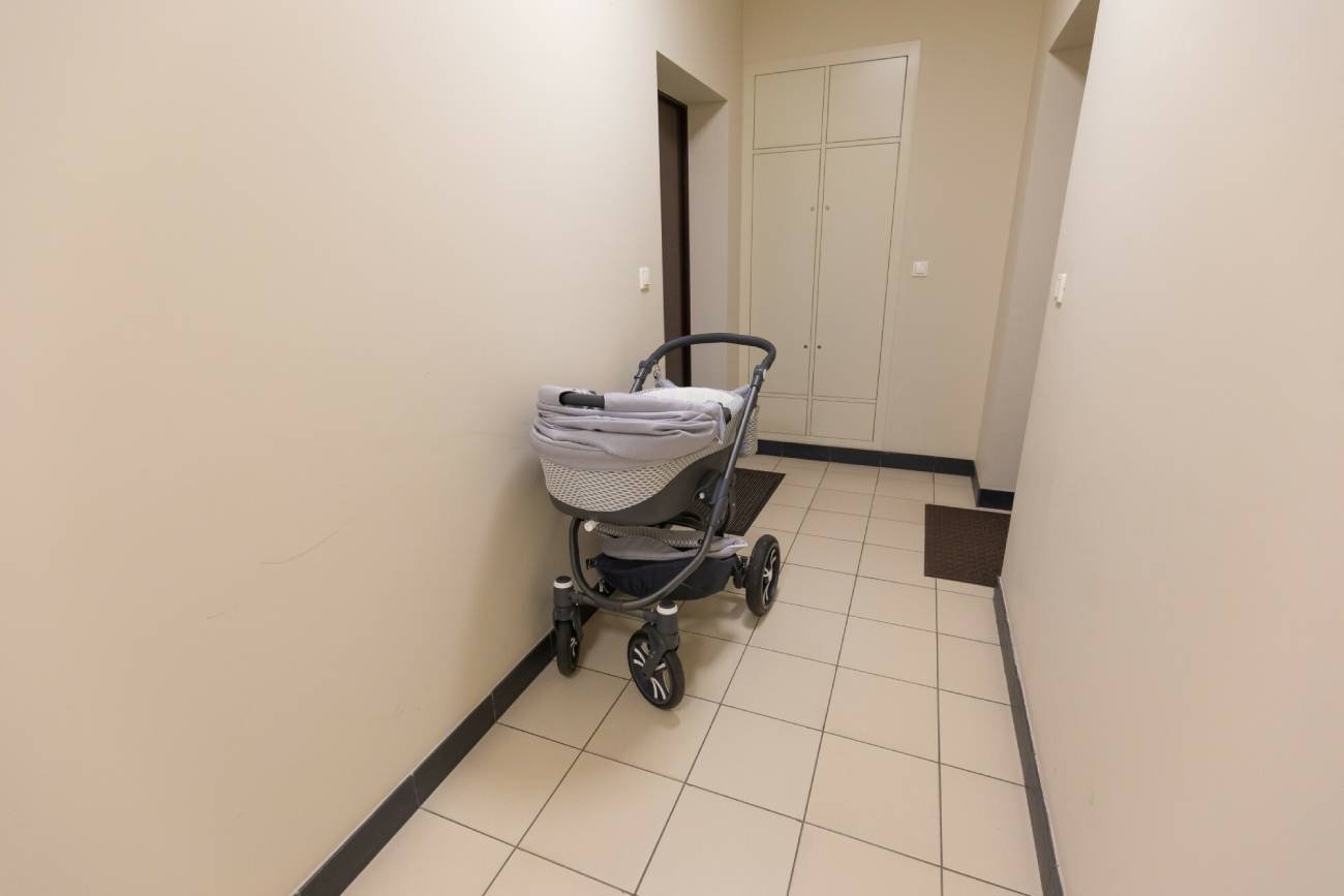 Wózek zostawiony na klatce schodowej koło wejścia do mieszkania.