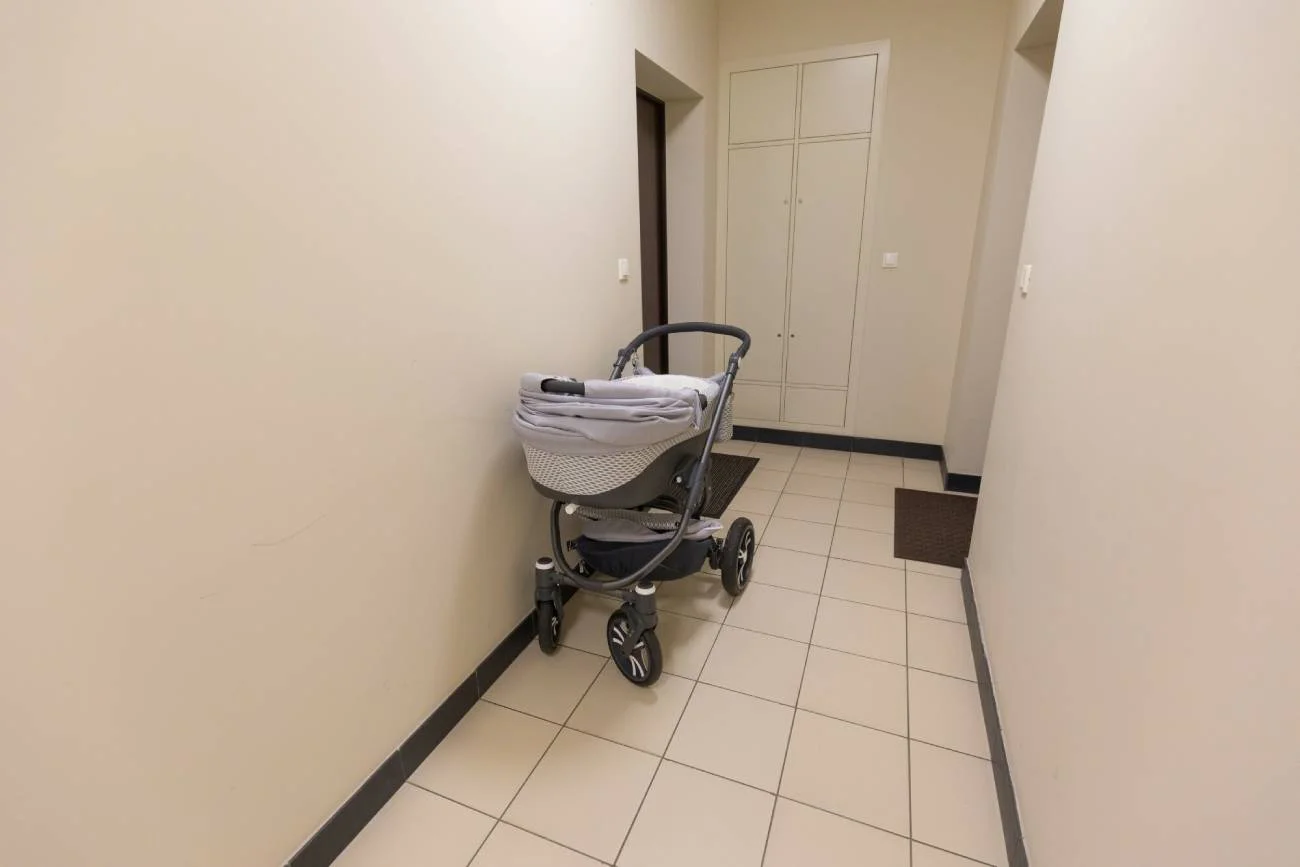 Wózek zostawiony na klatce schodowej koło wejścia do mieszkania.