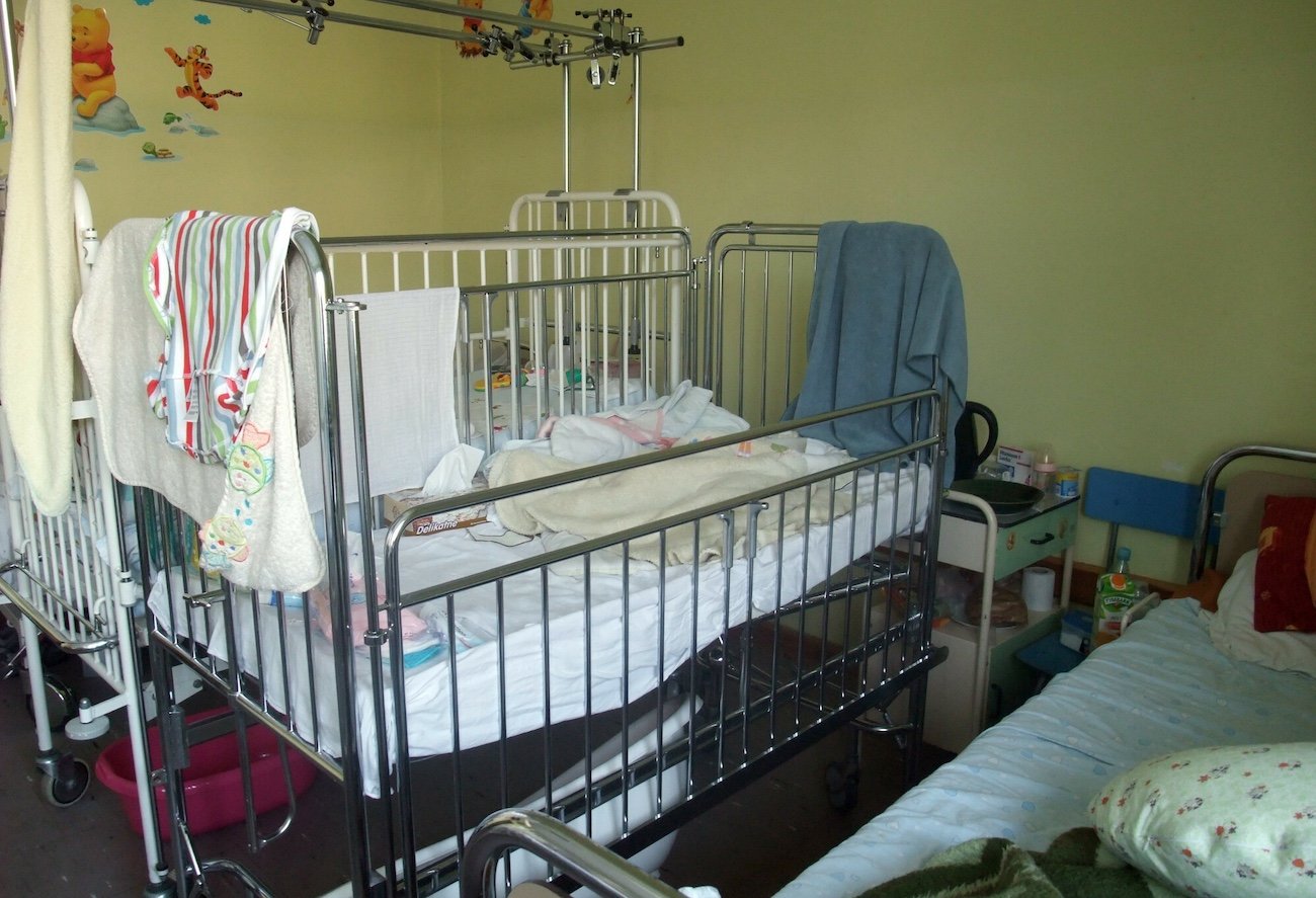 "Leży w łóżeczku o zimnych, metalowych prętach, w zielonej pościeli w sówki…".