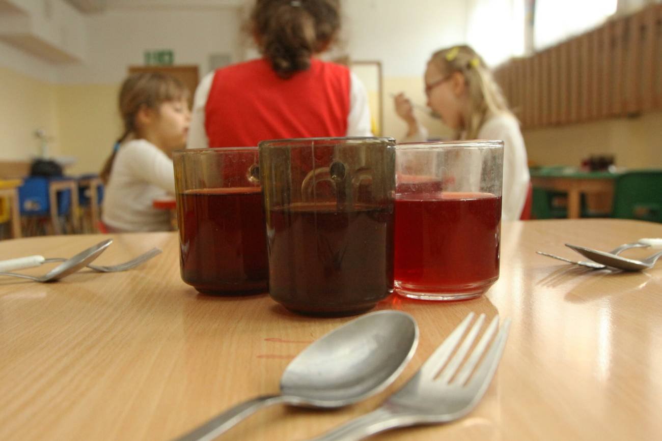 Szkolna stołówka i dzieci jedzące posiłek.