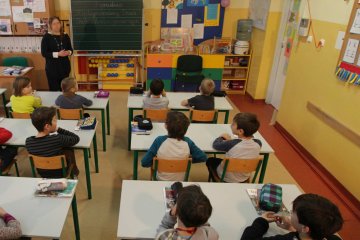 Polonistka prowadzi z uczniami lekcję i ocenia ich ocenami opisowymi.