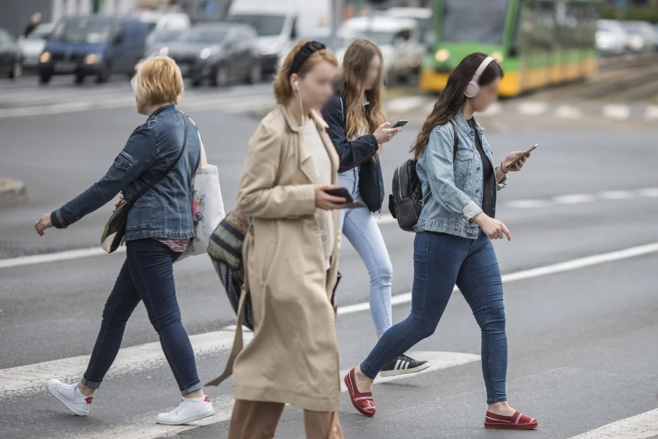 kobiety idą przez ulicę ze smartfonami w dłoniach kobiety idą przez ulicę ze smartfonami w dłoniach