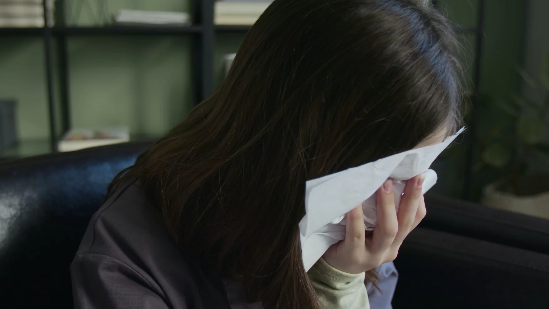 Dziewczynka płacze i trzyma chusteczkę przy twarzy.