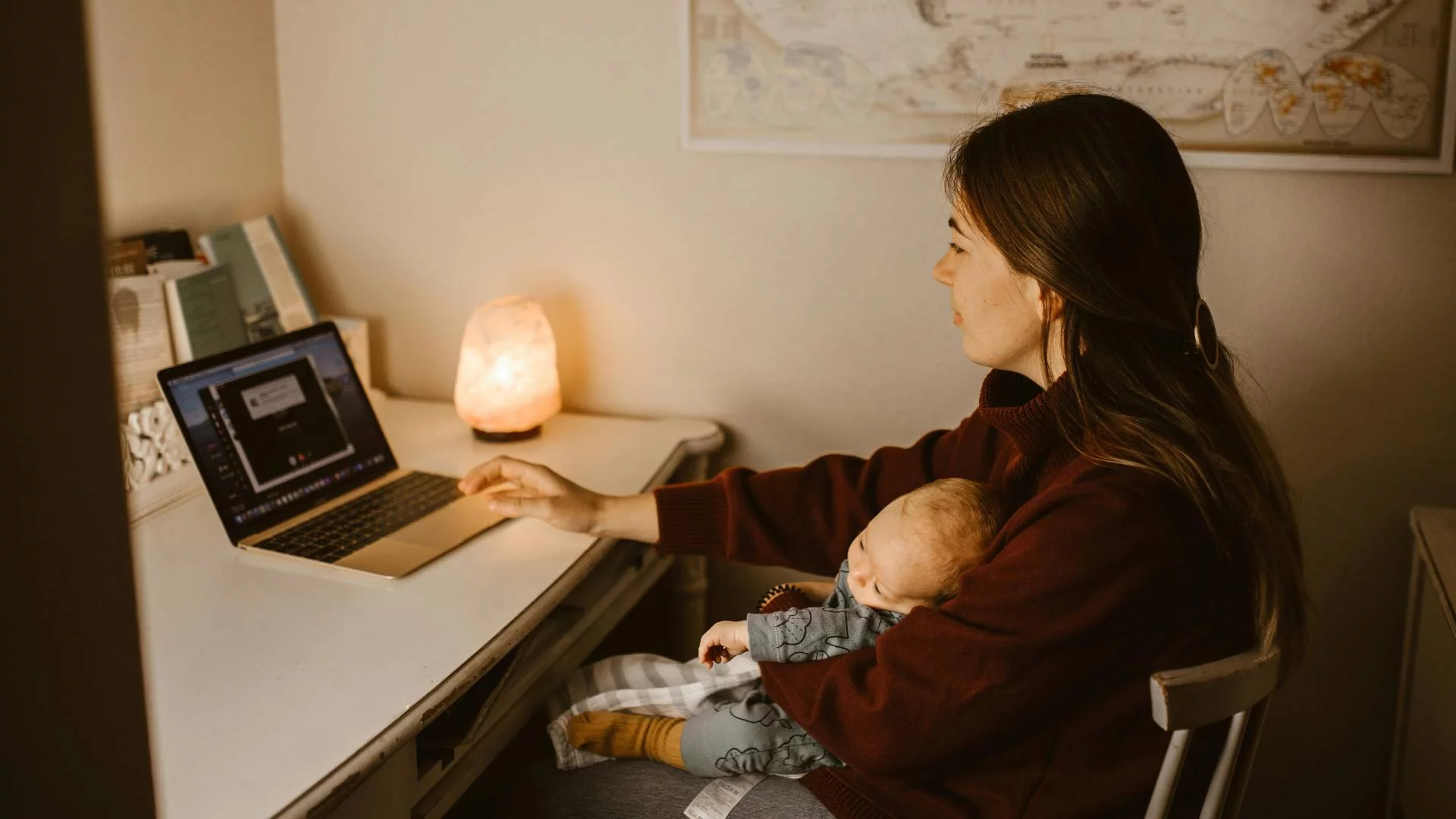 młoda mama z niemowlakiem w ramionach pracuje przed komputerem młoda mama z niemowlakiem w ramionach pracuje przed komputerem