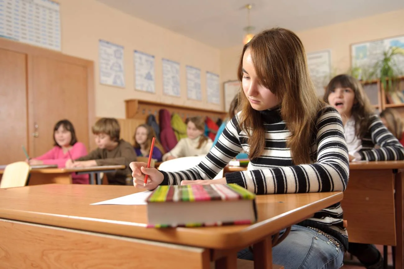 Uczniowie na lekcji siedzą w ławkach. Uczniowie na lekcji siedzą w ławkach.