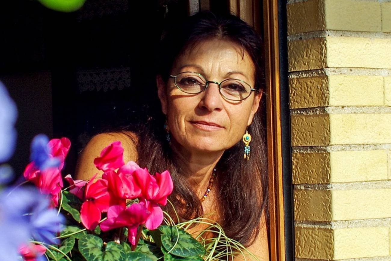 Kobieta, która jest babcią, wygląda przez okno.