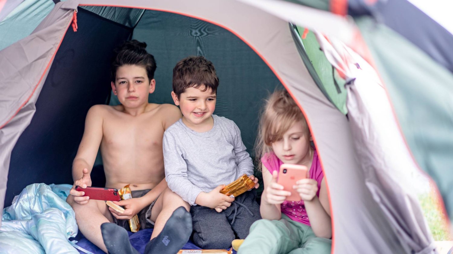 dzieci w namiocie patrzą w ekrany smartfonów