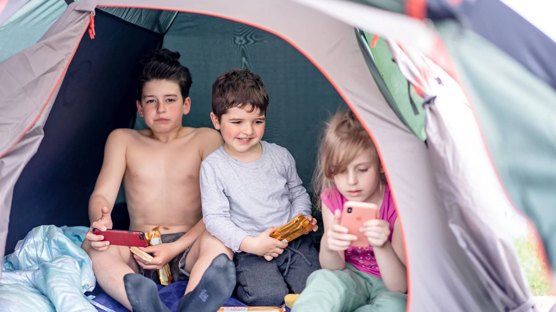 dzieci w namiocie patrzą w ekrany smartfonów dzieci w namiocie patrzą w ekrany smartfonów