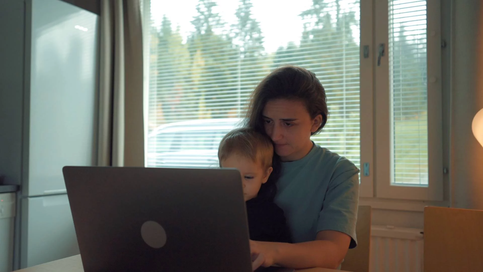 kobieta matka pracuje przy laptopie w domu z dzieckiem na kolanach