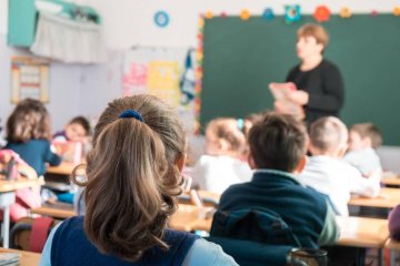 Uczniowie na lekcji siedzą w ławkach i słuchają nauczyciela.