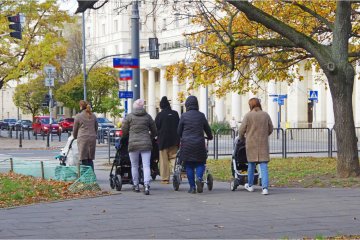 Grupa matek z wózkami na spacerze.