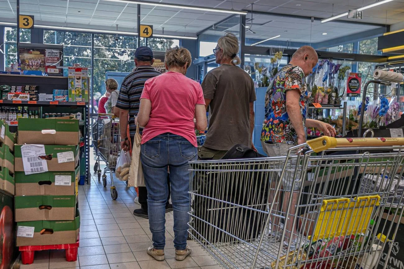 Ludzie stoją w Biedronce w kolejce do kasy.