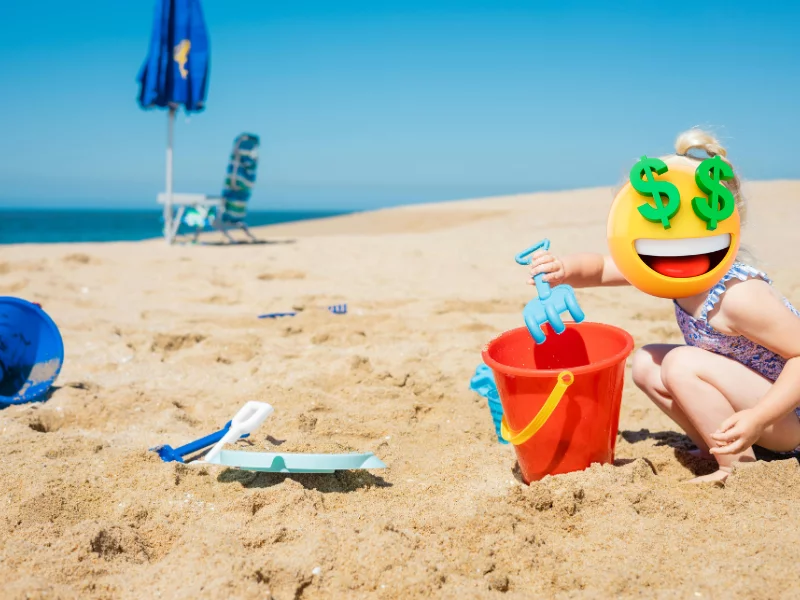Dziecko bawiące się na plaży z buzią zasłoniętą emotikonem