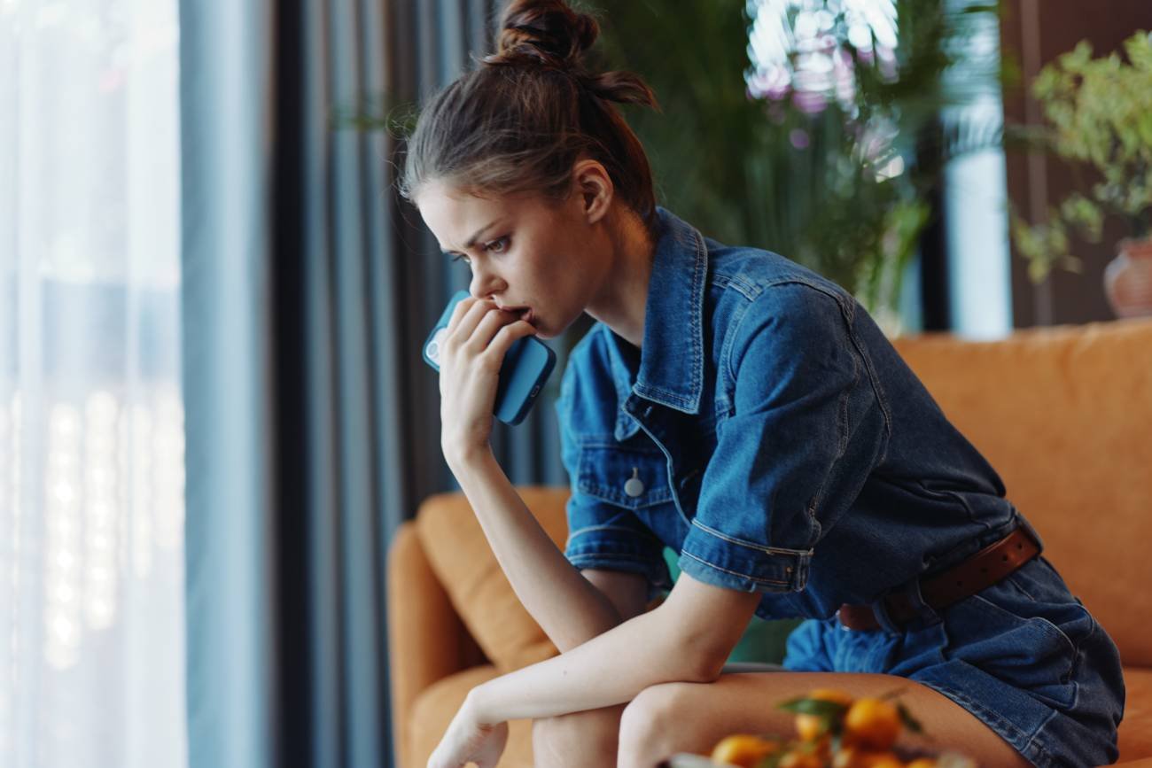 Zmartwiona kobieta siedzi na kanapie. Zmartwiona kobieta siedzi na kanapie.