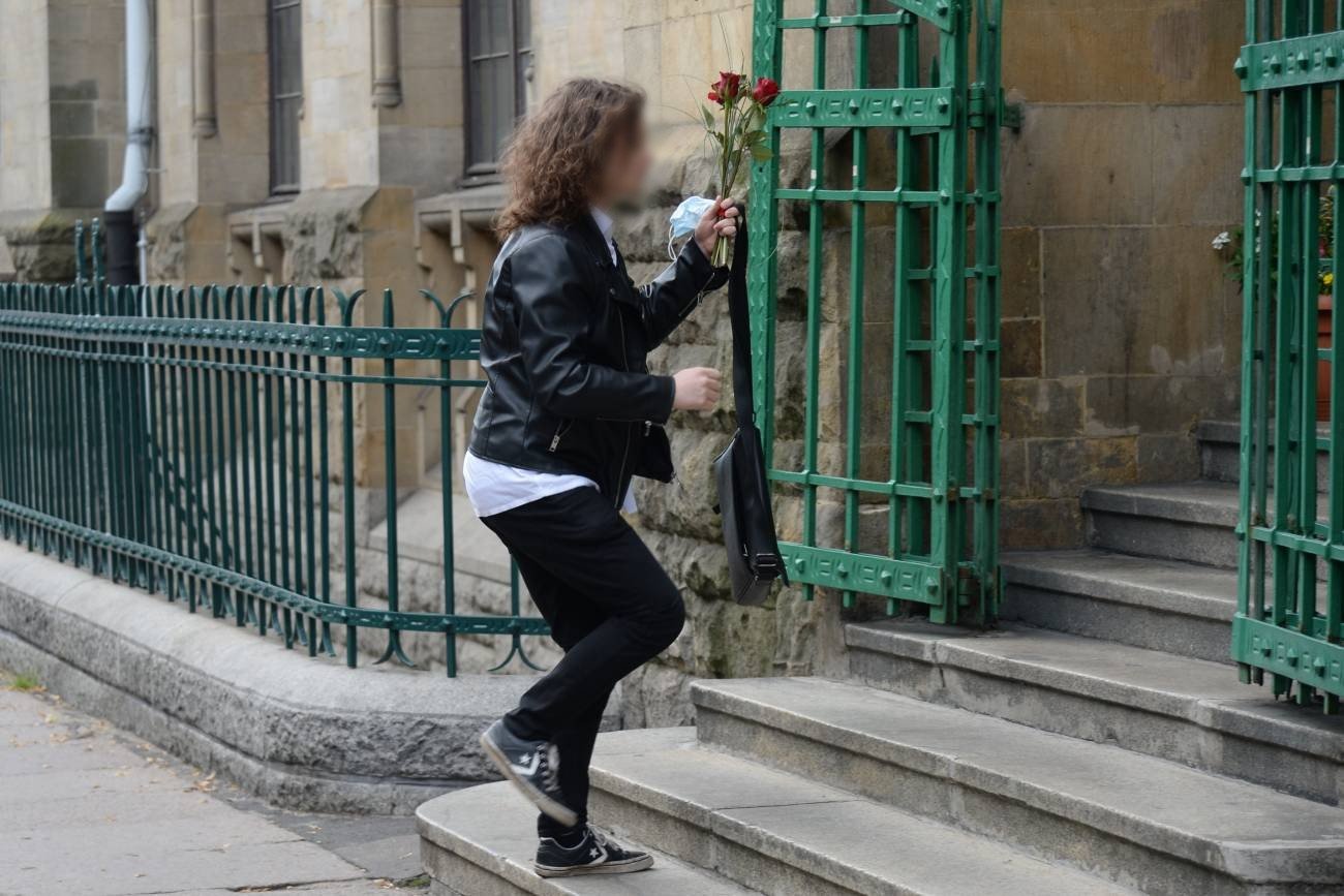 uczennica idzie na zakończenie roku szkolnego z kwiatami