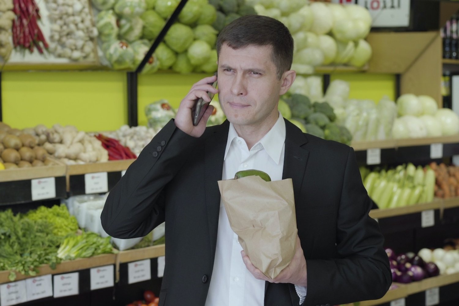 Na zdjęciu widać mężczyznę w supermarkecie rozmawiającego przez telefon.