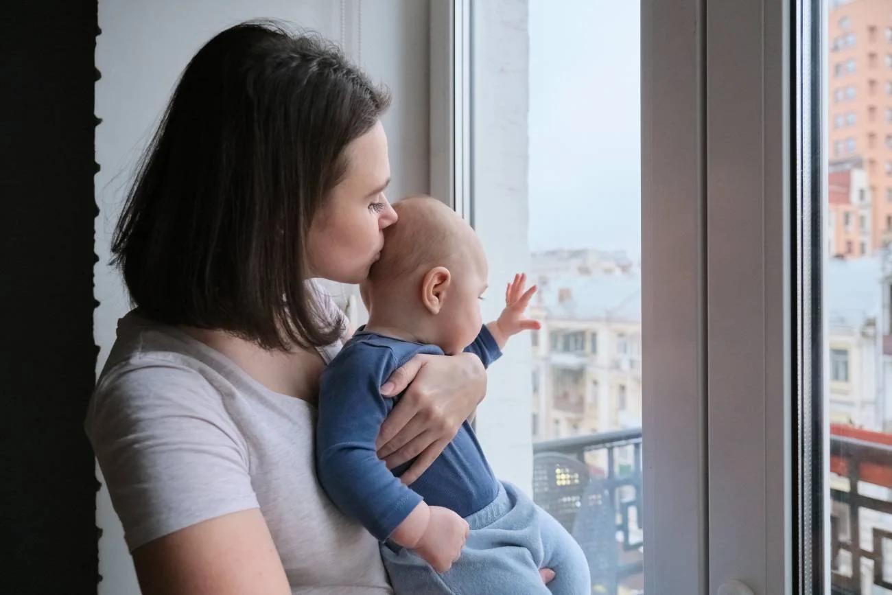 Smutna, samotna mama z niemowlakiem na rękach.