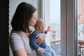 Smutna, samotna mama z niemowlakiem na rękach.