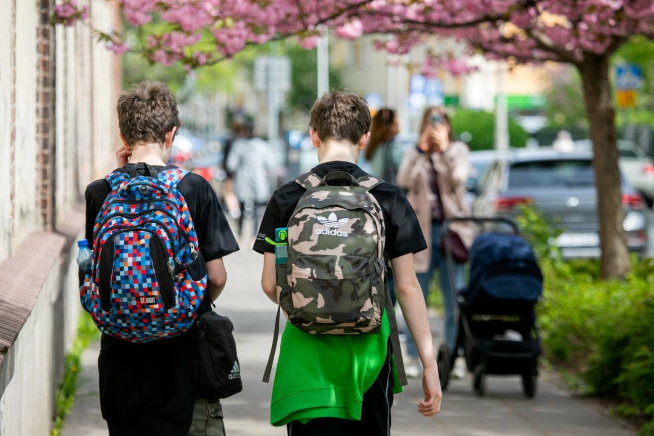 Nastolatki idący z plecakami przez miasto.