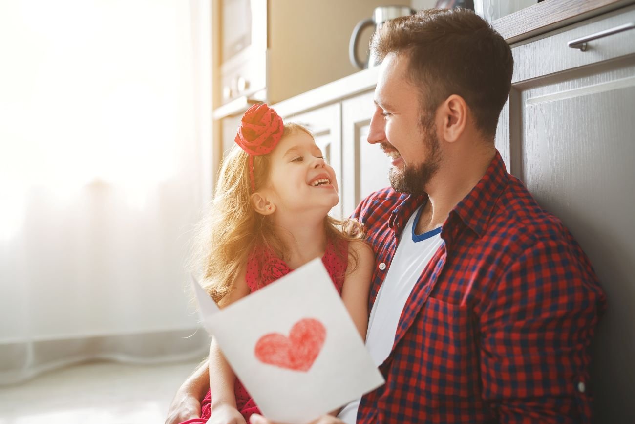 Córka daje laurkę tacie na Dzień Ojca