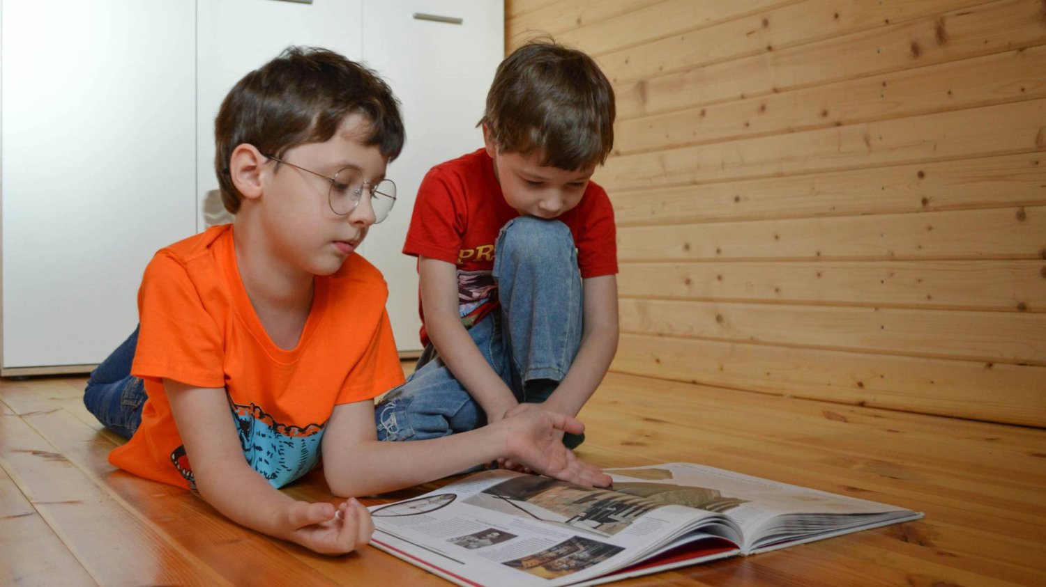 dwaj bracia przeglądają na podłodze książkę