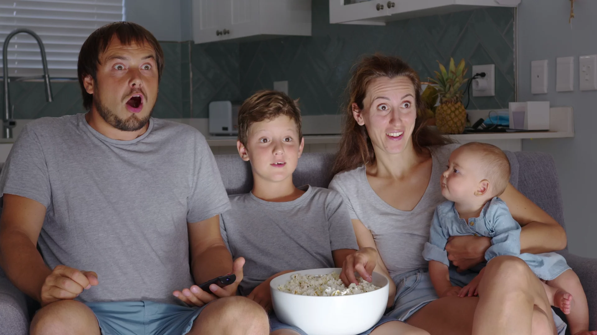 Bajki i filmy na Halloween – najlepsze propozycje dla dzieci i dorosłych Na zdjęciu rodzina siedzi na kanapie i ogląda tv – po minach widać, że film czy bajka mogą wzbudzać strach