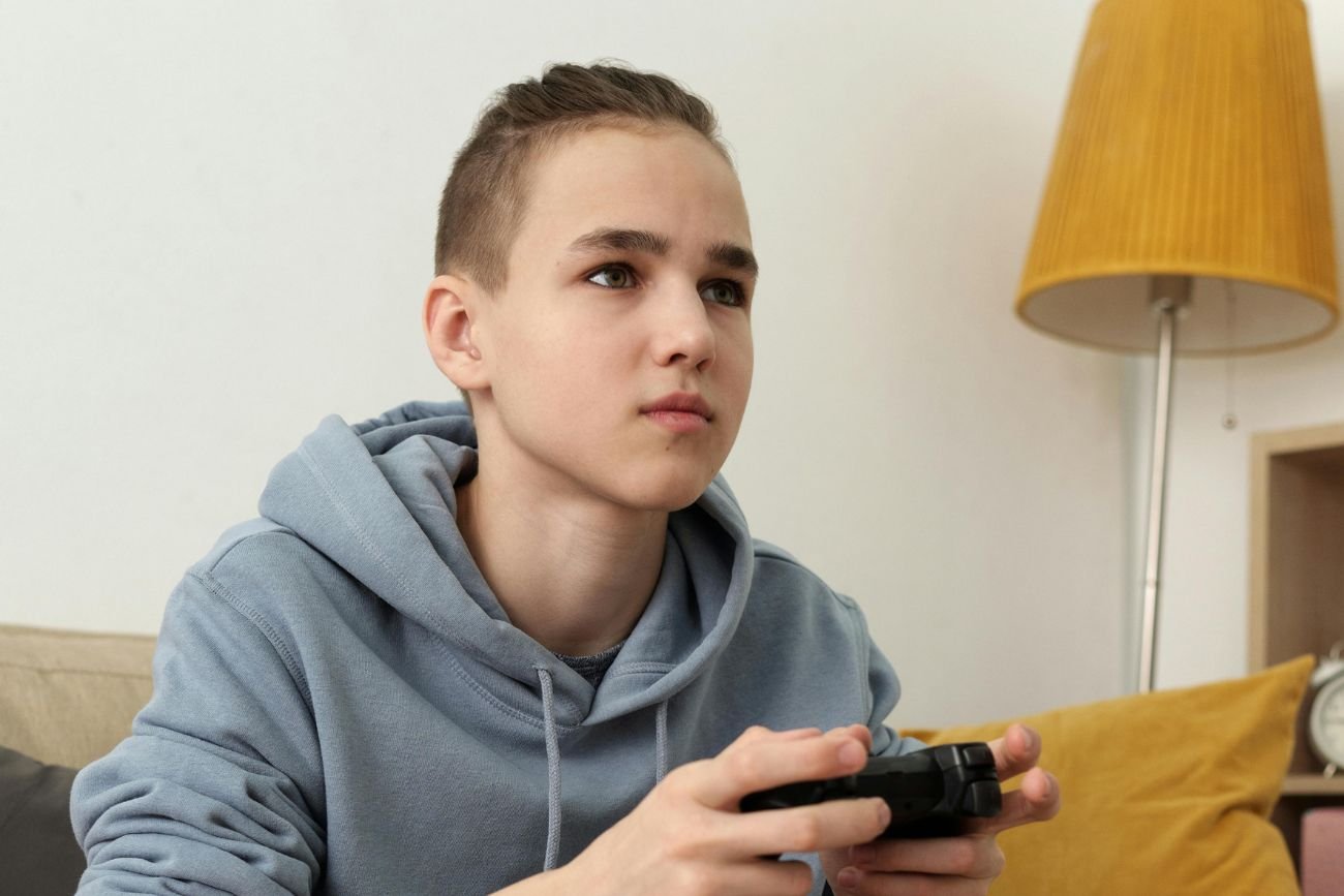 Chłopak z pokolenia alfa/zet polega na technologii, co może przynieść negatywne skutki. nastolatek grający na konsoli