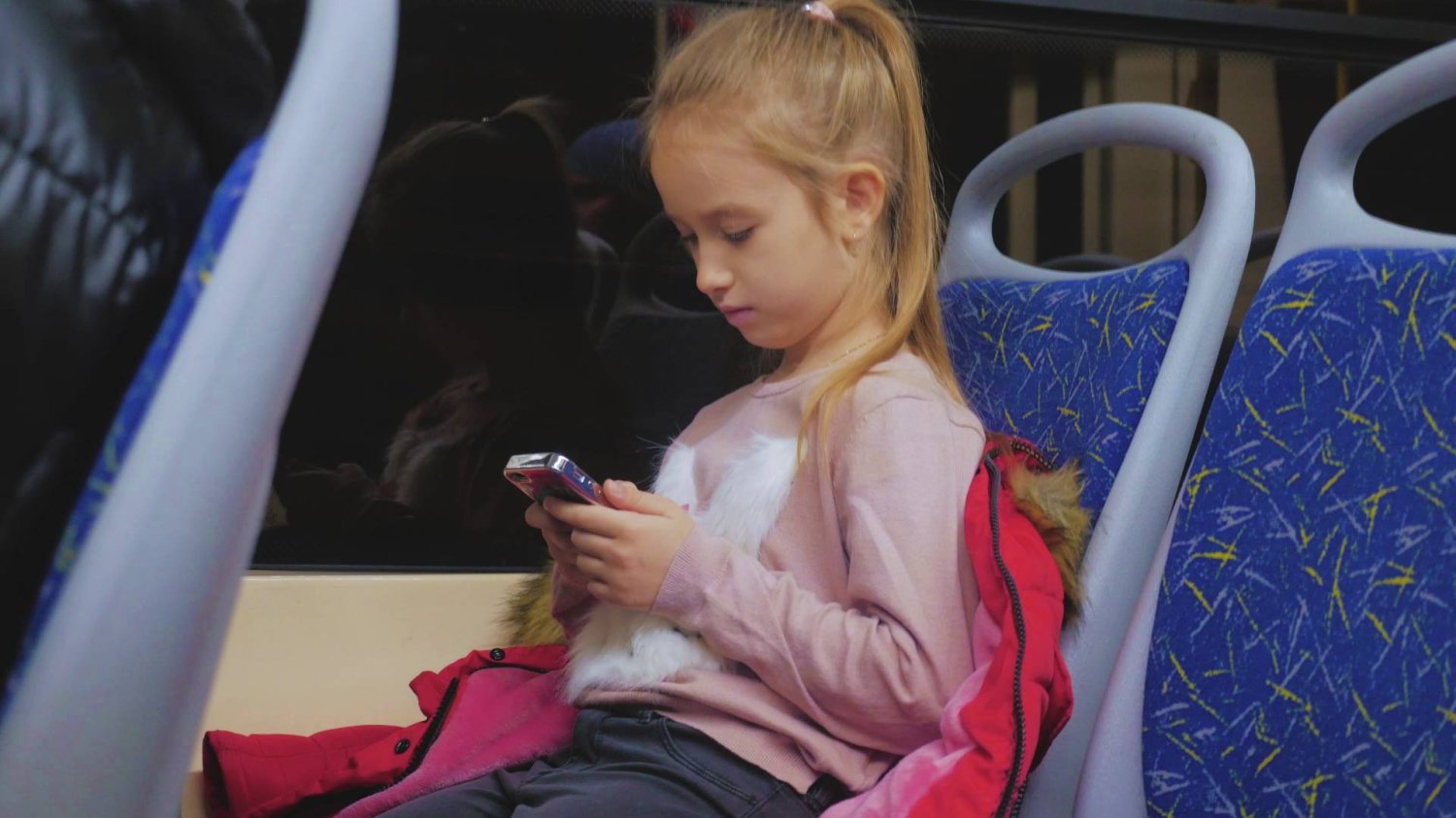 dziewczynka jedzie komunikacją miejska i scrolluje ekran smartfona