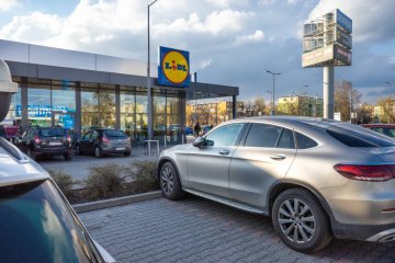 Auta na parkingu pod sklepem.