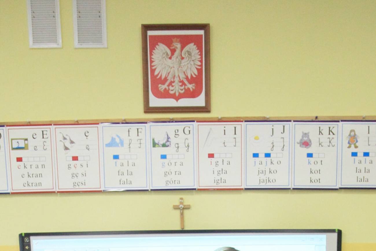 Klasa lekcyjna z krzyżem na ścianie.