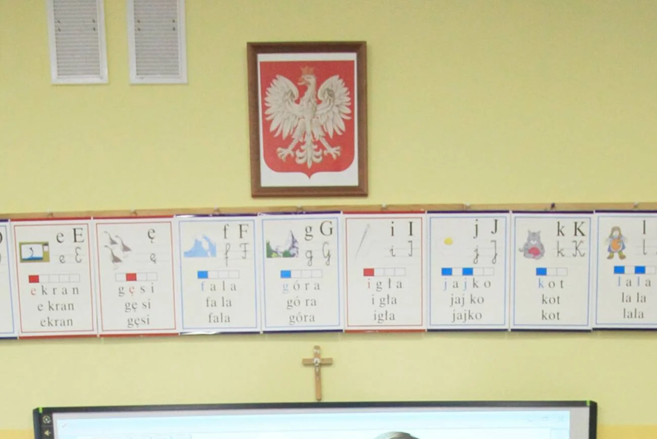 Klasa lekcyjna z krzyżem na ścianie.