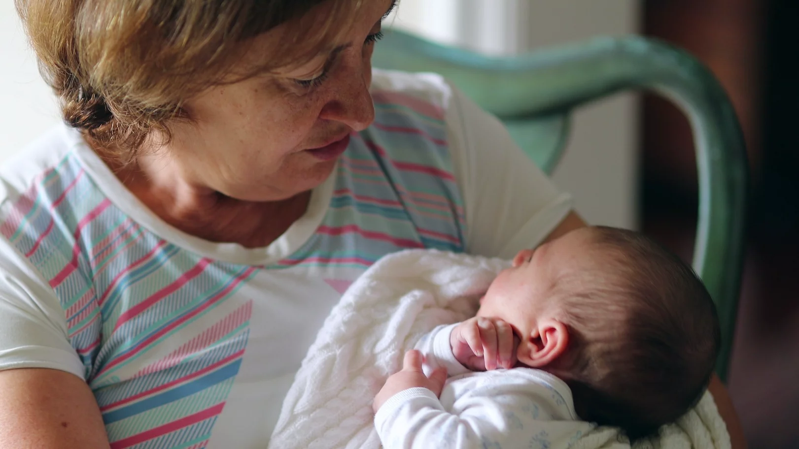 Na zdjęciu starsza kobieta trzyma noworodka.