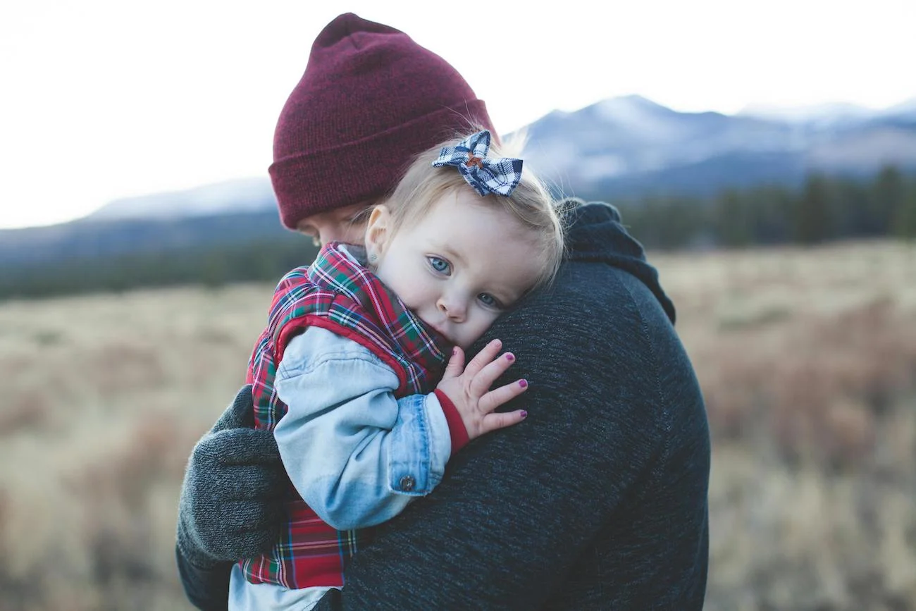 smutne dziecko w ramionach rodzica