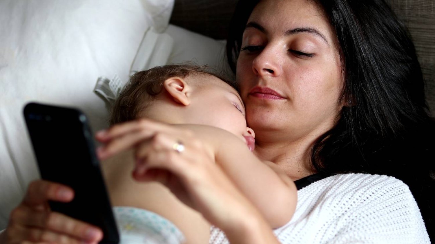 młoda mama czyta komentarze o macierzyństwie na smartfonie młoda mama czyta komentarze o macierzyństwie na smartfonie