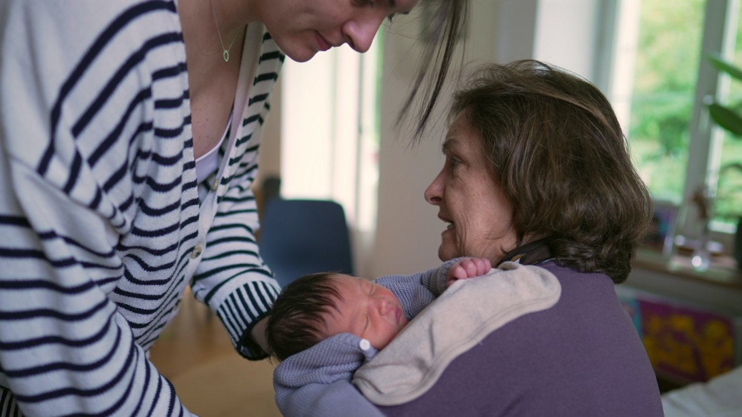 Na zdjęciu babcia zajmuje się dzieckiem, mama próbuje je "przejąć".