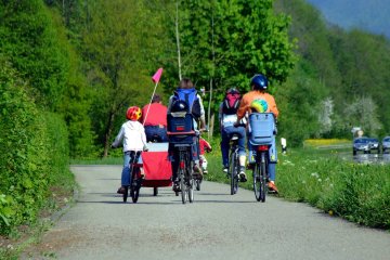 Rodzice i dzieci jadą na rowerach po chodniku.