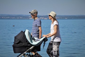 rodzice z czarnym wózkiem na spacerze